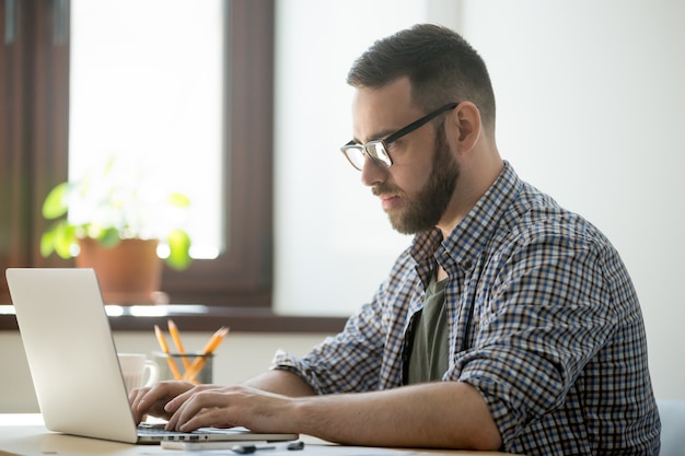 Geração milenar homem trabalhando no computador portátil para resolver o problema Foto gratuita