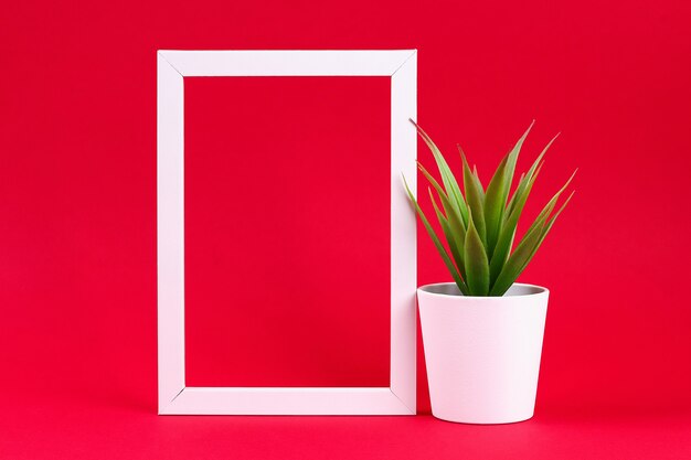 Grama verde artificial em um potenciômetro pequeno branco no frame branco em um fundo vermelho de borgonha. Foto Premium
