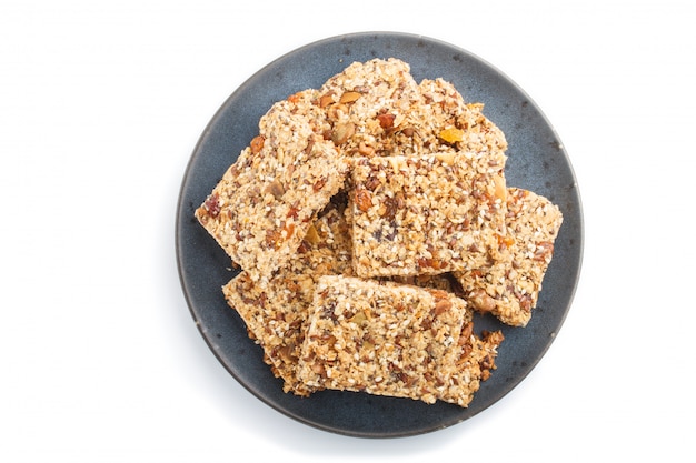 Granola caseira de flocos de aveia datas secas damascos passas nozes no prato de cerâmico azul isolado no fundo branco Foto Premium