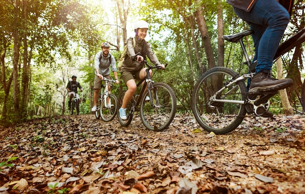 Grupo de amigos andam de bicicleta de montanha na floresta juntos Foto gratuita