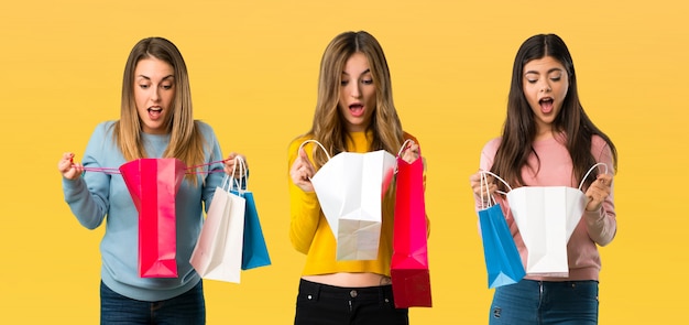 Grupo de pessoas com roupas coloridas surpreso, mantendo um monte de sacos de compras Foto Premium