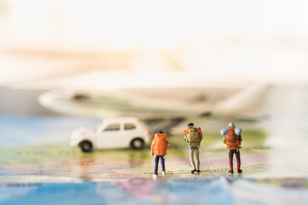 Grupo de viajantes miniatura mini figuras com mochila andando no mapa para modelo de avião e carro de brinquedo branco Foto Premium