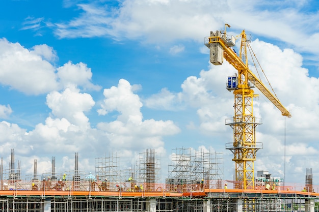 Guindastes de construção e prédio sob a construção contra o céu azul. Foto Premium