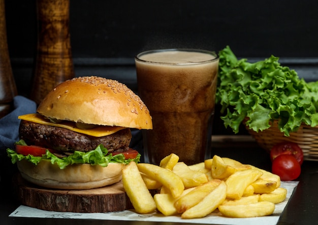 Hambúrguer de carne com queijo, alface, tomate servido com batata frita e coque Foto gratuita