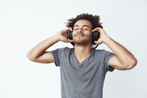 Homem africano feliz sorrindo ouvindo música em fones de ouvido. Foto gratuita