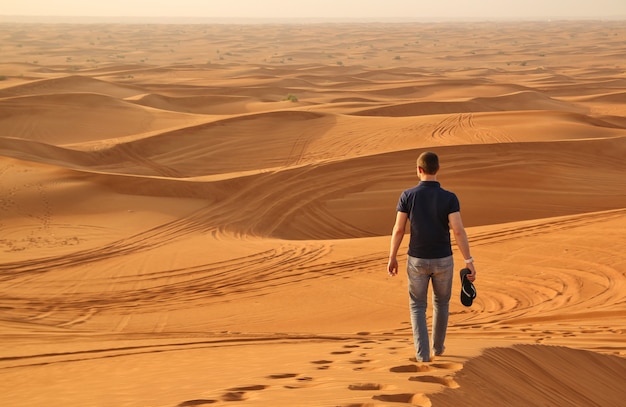 Homem andando sozinho no deserto ensolarado ao lado de dubai ...