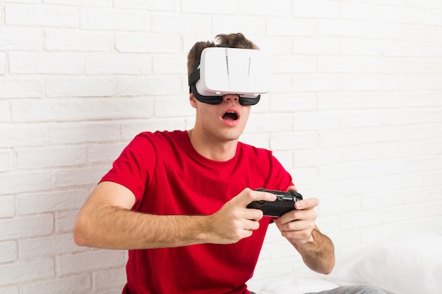 Homem caucasiano de adolescente usando óculos de realidade virtual e controlador de jogo Foto Premium