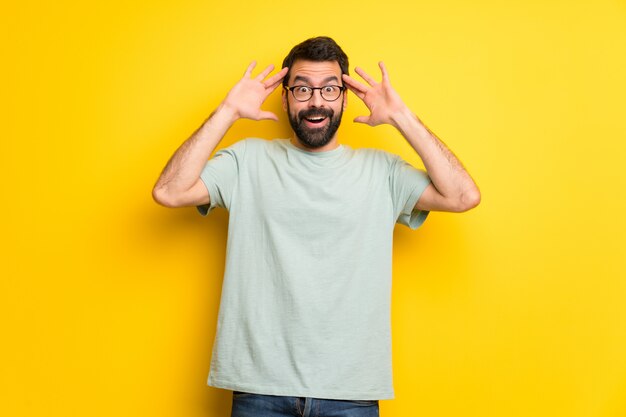 Homem com barba e camisa verde com surpresa e expressão facial chocada Foto Premium