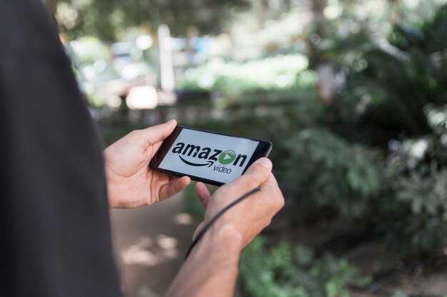 Homem, com, smartphone, mostrando, amazon, principal, vídeo, app Foto gratuita