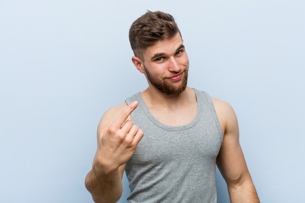 Homem de aptidão bonito jovem apontando com o dedo para você como se convidando chegar mais perto. Foto Premium