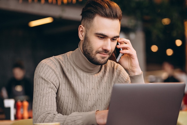 Homem de negócios bonito trabalhando no computador e tomando café em um café Foto gratuita
