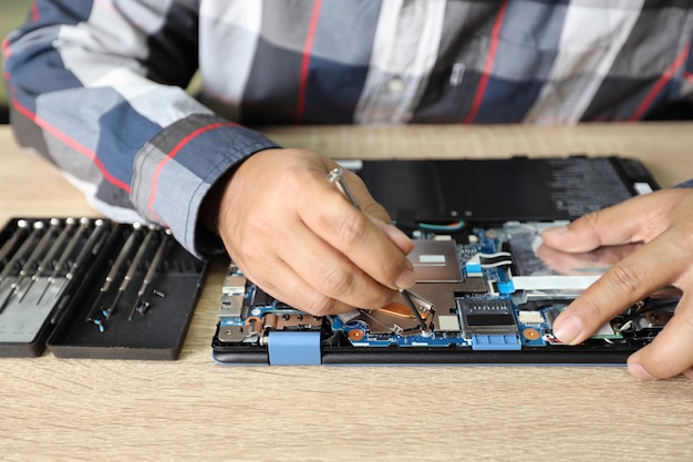 Homem de técnico usando a chave de fenda para consertar ou atualizar o computador portátil Foto Premium