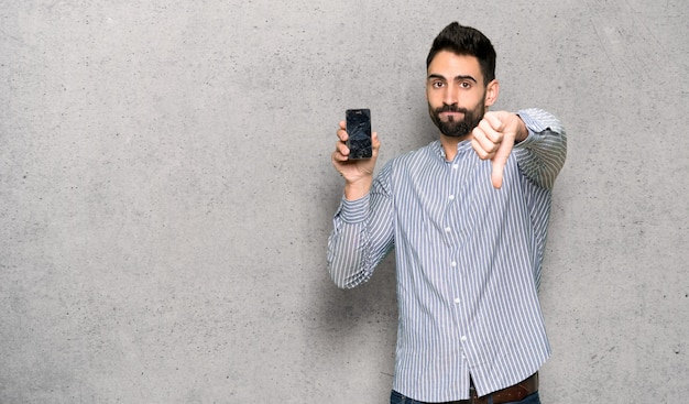 Homem elegante, com, camisa, com, perturbado, segurando, quebrada, smartphone, sobre, textured, parede Foto Premium