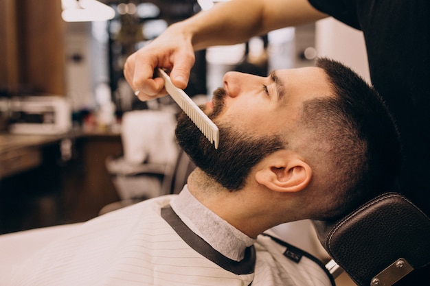 Homem em um salão de barbearia fazendo o corte de cabelo e barba Foto Grátis