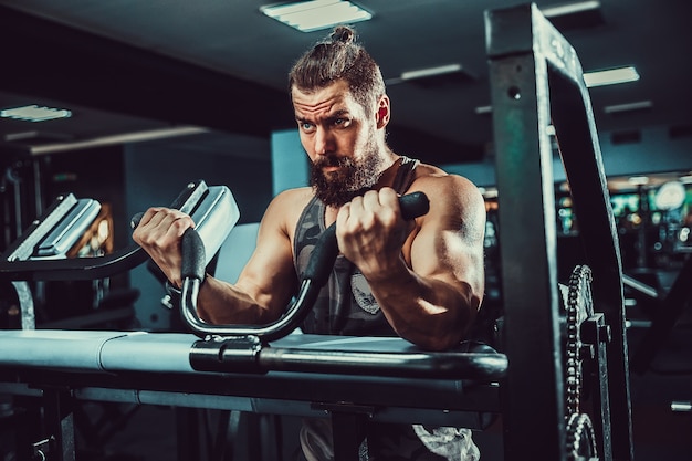 Homem fazendo exercício de peso pesado para bíceps na máquina em um ginásio  | Foto Premium