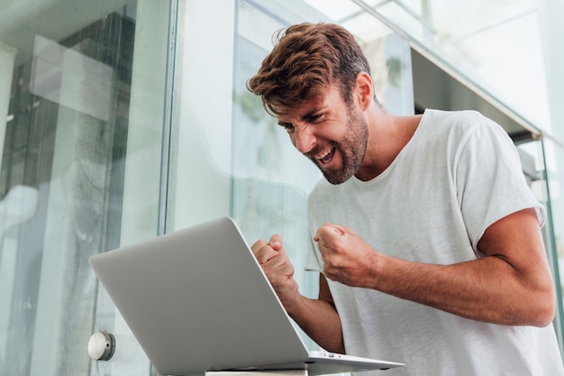 Homem feliz comemorando com notebook Foto gratuita