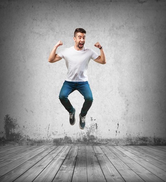 Homem feliz que salta no chão de madeira Foto gratuita