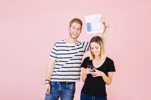 Homem feliz segurando os polegares para cima gesto mulher usando o celular Foto gratuita