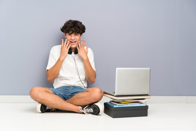 Homem jovem, com, seu, laptop, sentando, um, a, chão, com, surpresa, expressão facial Foto Premium