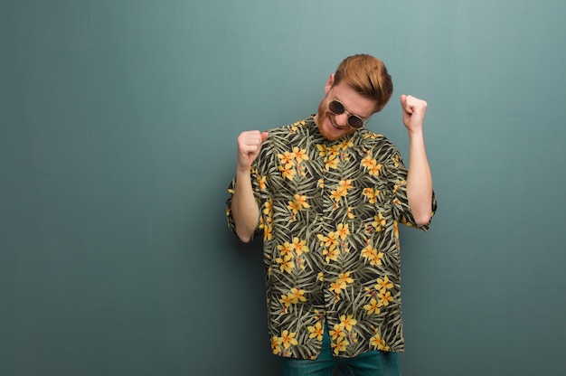 Homem jovem ruiva vestindo roupas de verão exóticas dançando e se divertindo Foto Premium