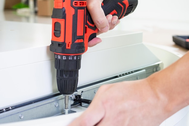 Homem montando móveis de mesa branca em casa usando chave de fenda sem