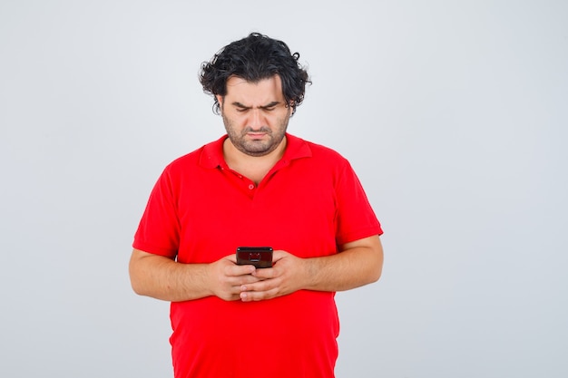 Homem Segurando O Telefone Nas Mãos Com Uma Camiseta Vermelha E Olhando