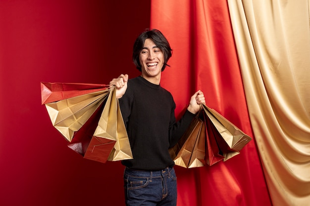 Homem sorridente posando com sacolas de compras para o ano novo chinês Foto gratuita