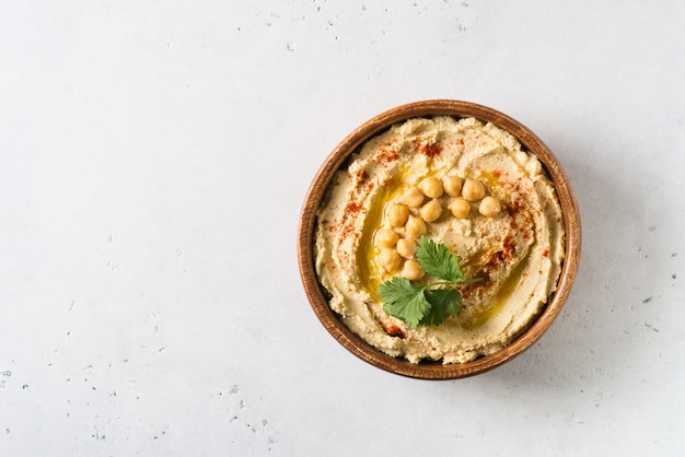 Hummus mergulho com grão de bico e salsa em placa de madeira no fundo branco Foto Premium