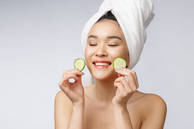 Imagem asiática nova dos cuidados com a pele das mulheres da beleza com o pepino no estúdio branco do fundo. Foto Premium