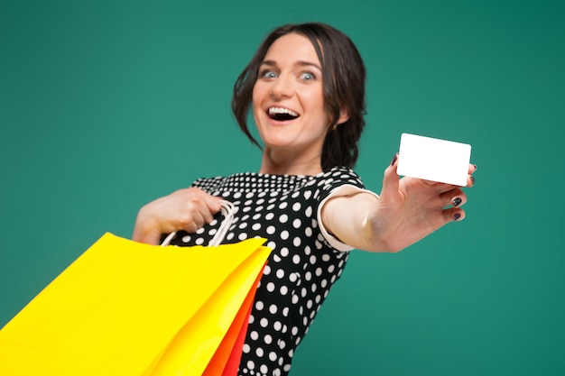 Imagem de mulher bonita em roupas salpicadas de pé com compras e fraque nas mãos Foto Premium