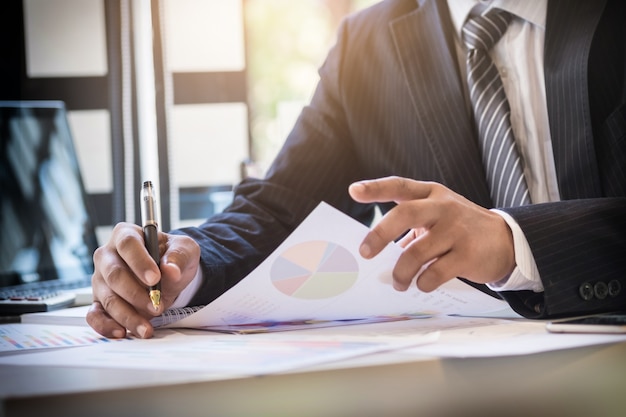 Início do processo de trabalho. empresário que trabalha na mesa de madeira com novo projeto de finanças. caderno moderno na mesa. pen segurando a mão. Foto Premium
