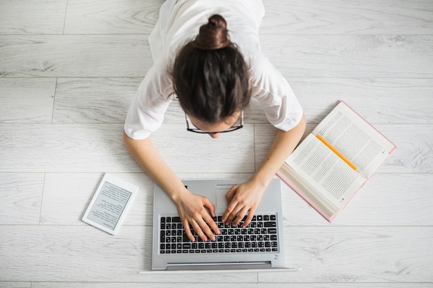 Irreconhecível mulher usando laptop perto de livro Foto gratuita