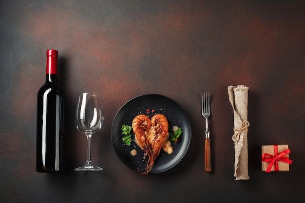 Jantar romântico com camarões e vinho coração-dados forma em um fundo marrom. vista superior com espaço para texto Foto Premium
