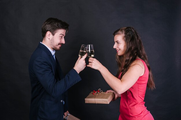 Jovem, alegre, mulher, agarrar, óculos, de, bebida, com, homem, e, segurando, presente, caixas Foto gratuita