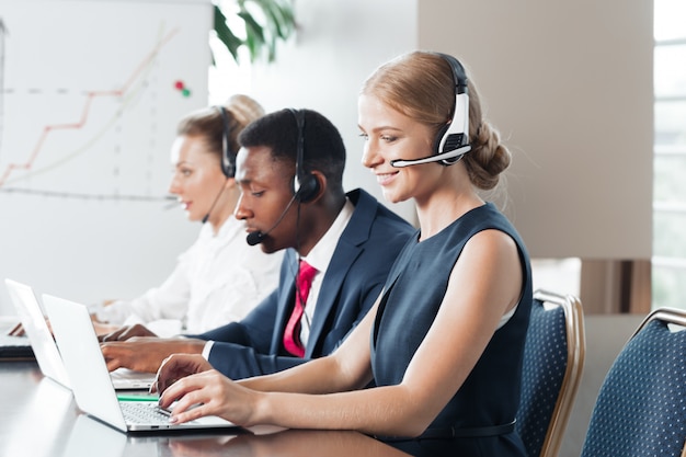 Jovem atraente, trabalhando em um call center com seus colegas Foto Premium