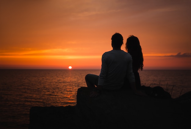 Jovem casal apaixonado contra o pôr do sol no mar Foto