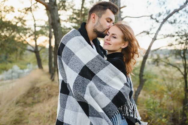 Jovem casal romântico apaixonado em um abraço carinhoso e se aquece com uma manta Foto Premium