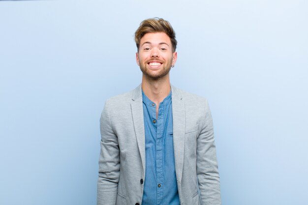 Jovem empresário, olhando feliz e pateta, com um sorriso largo, divertido e maluco e olhos bem abertos em azul Foto Premium