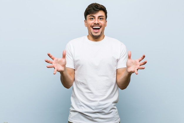 Jovem homem caucasiano vestindo uma camiseta branca comemorando uma vitória ou sucesso Foto Premium