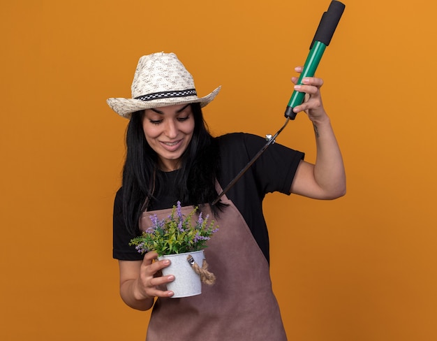 Jovem jardineira caucasiana sorridente usando uniforme e chapéu