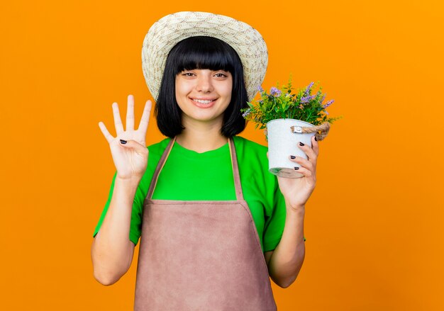 Jovem jardineira sorridente de uniforme usando chapéu de jardinagem