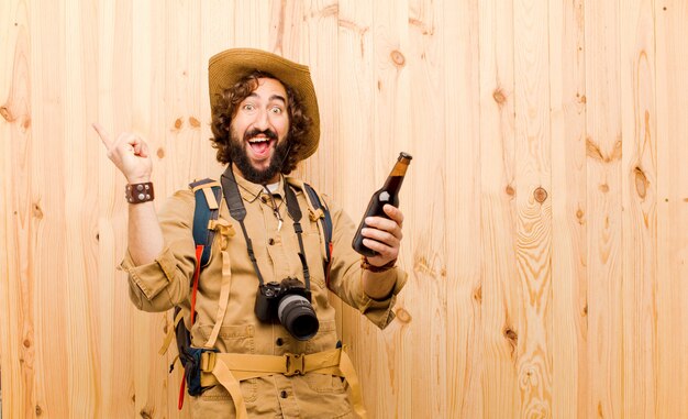 Jovem louco explorador com chapéu de palha e mochila em fundo de madeira Foto Premium