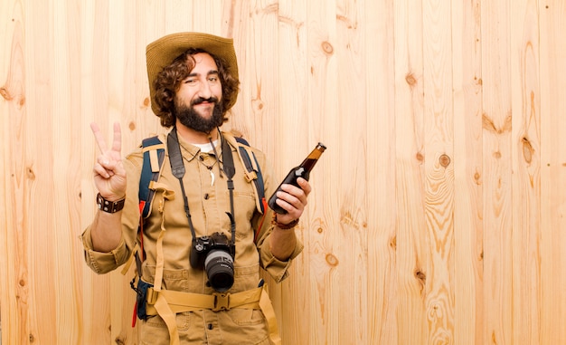 Jovem louco explorador com chapéu de palha e mochila em fundo de madeira Foto Premium