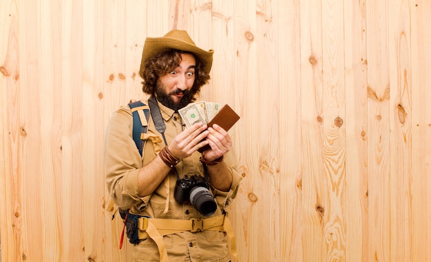 Jovem louco explorador com chapéu de palha e mochila em fundo de madeira Foto Premium