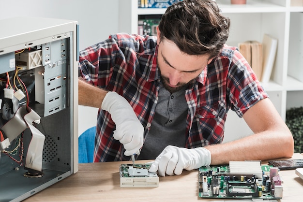Jovem, macho, técnico, desgastar, luvas, afixando, computador, motherboard, com, chave fenda Foto gratuita