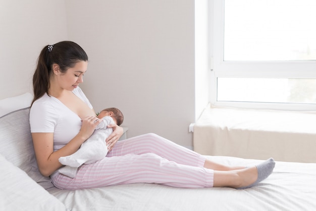 Jovem Mãe Amamentando Amamentando E Abraçando O Bebê Foto Premium 