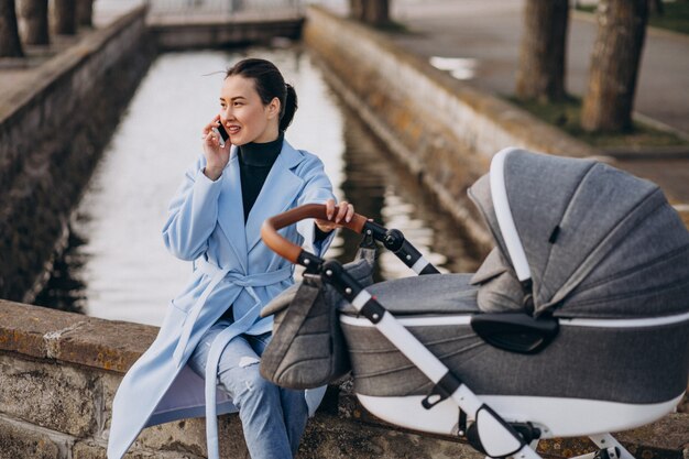 Jovem, mãe, sentando, com, carruagem bebê, parque Foto gratuita