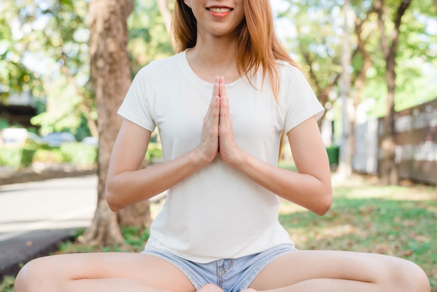 Jovem mulher asiática yoga ao ar livre manter a calma e medita enquanto pratica ioga Foto Grátis
