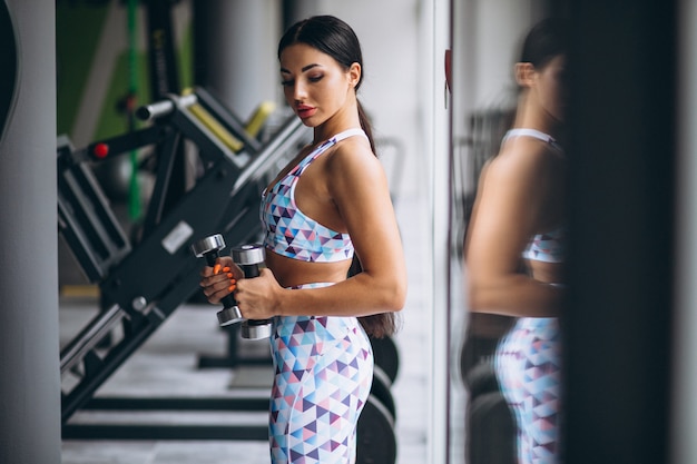 Jovem mulher atraente na academia com halteres Foto gratuita
