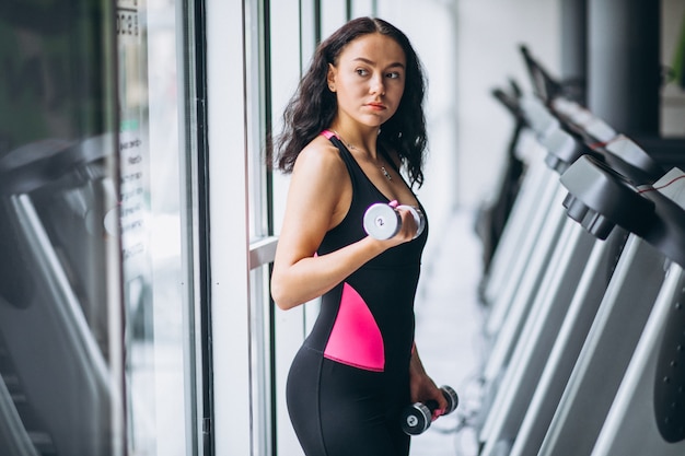 Jovem mulher atraente na academia com halteres Foto gratuita